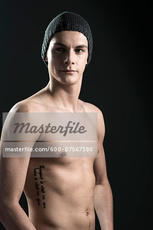 Close-up portrait of young man wearing toque, studio shot on black background