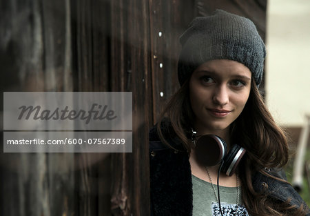 Portrait of teenage girl outdoors, wearing hat and headphones around neck, Germany