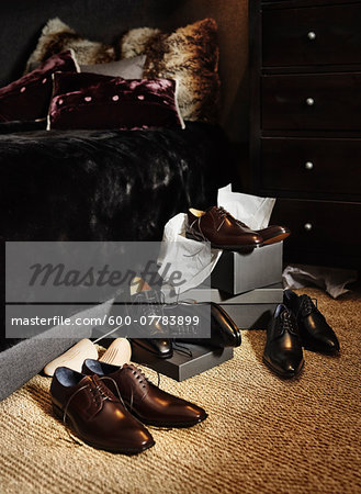 New, men's dress shoes and boxes on floor beside bed in bedroom, studio shot