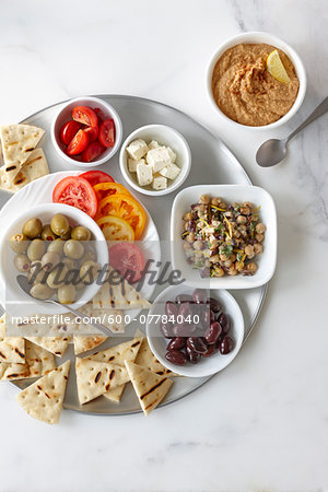 Overhead View of Appetizers, Chickpea Salad, Feta, Cherry and Sliced Tomatoes, Green and Black Olives, Hummus, and Grilled Pita