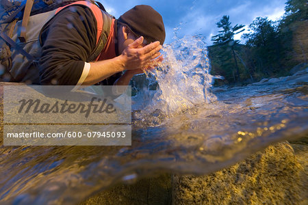 Clsoe-up of a man rinsing off his face to cool down after a hike in New Hampshire, USA