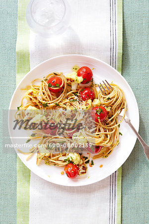 Spaghetti with Tomatoes and Roasted Cauliflower, on a plate with a fork, on a cloth napkin, studio shot