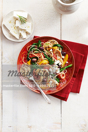 Greek style Spaghetti with chicken, feta, olives, peppers and rapini, studio shot on white background Greek style Spaghetti with chicken, feta, olives, peppers and rapini, studio shot on white background