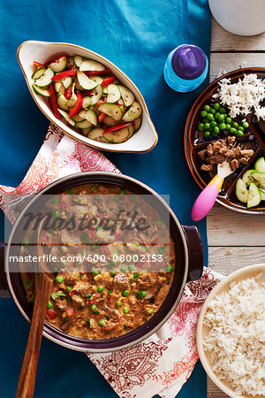 Lamb Curry in a Pot with Rice and Cucumber Salad and plate with child's portion, studio shot Lamb Curry in a Pot with Rice and Cucumber Salad and plate with child's portion, studio shot