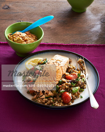 Baked Salmon with grain side dish with fork on plate and bowl of dipping sauce, studio shot Baked Salmon with grain side dish with fork on plate and bowl of dipping sauce, studio shot