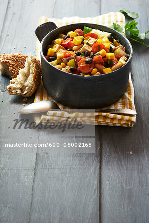 Tofu chilli in pot, with crusty bread on a gray, wooden table, studio shot Tofu chilli in pot, with crusty bread on a gray, wooden table, studio shot