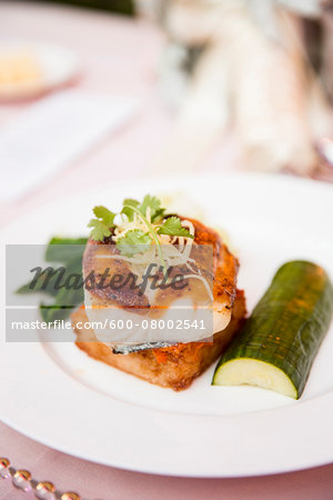 Close-up of glazed, fish filet with cucumber on a dinner plate, at an event, Canada