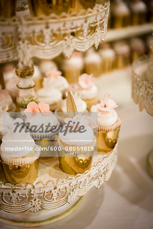 Vanilla Cupcakes In Gold Foil On Stands At Wedding Stock Photo