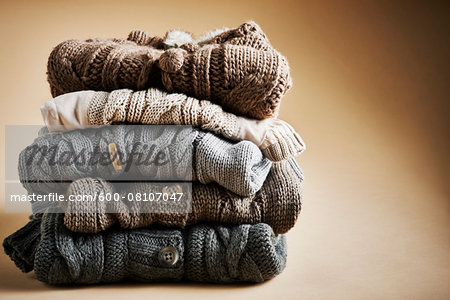 Stack of five cardigans, studio shot on brown background