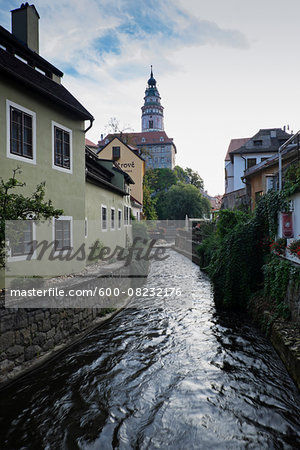 Residential buildings along canal of the Vltava River with the tower of the Cesky Krumlov Castle in the background, Cesky Krumlov, Czech Replublic.