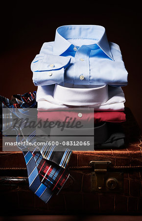 Stack of shirt with ties on suitcase in studio