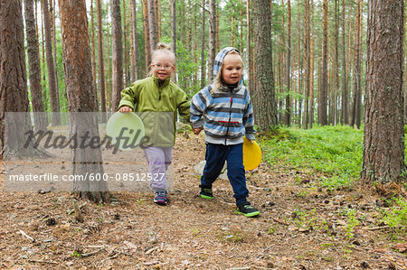 4 year old brother and sister walking with their frisbees through the woods, Sweden