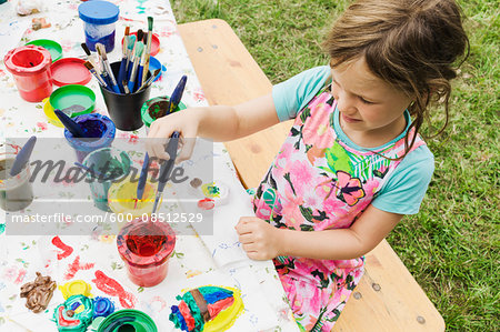 5 year old girl painting at a table in the garden, Sweden