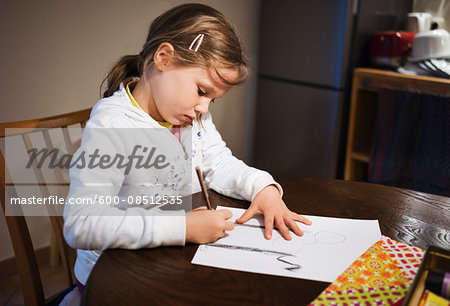 5 year old girl sitting at the table and drawing with a pencil, Germany