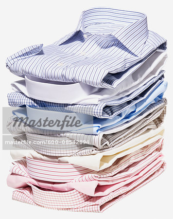 Stack of different coloured shirts on white background