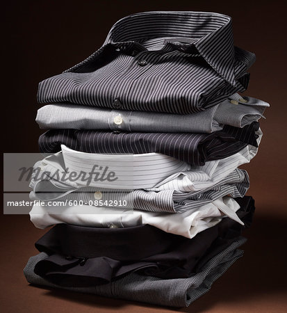 Stack of men's dress shirts on brown background