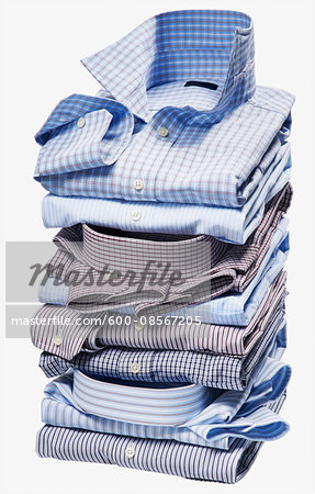 Stack of multi coloured checked and striped shirts on white background, studio shot