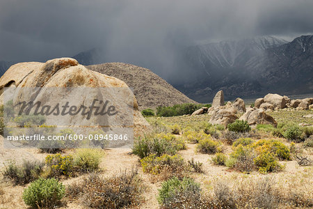 Rock formations of the Alabama Hills with storm clouds over the Sierra Nevada Mountains in the background in Eastern California, USA