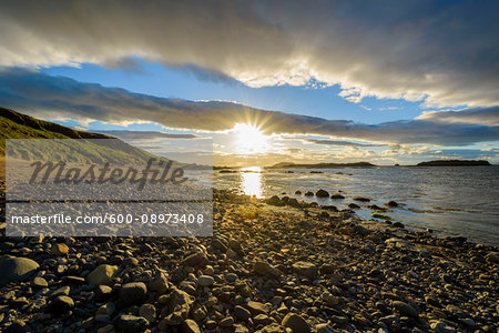 Sun shining over bay with rocky beach at sunset in North Berwick at Firth of Forth in Scotland, United Kingdom