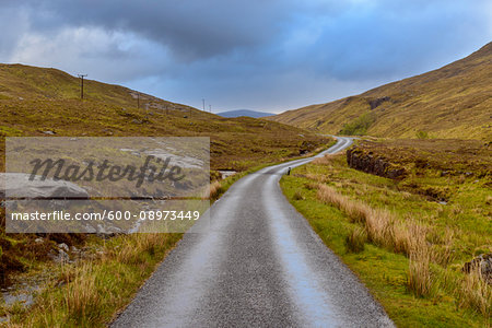 Winding road in the highlands with a cloudy sky at Glen Coe in Scotland, United Kingdom
