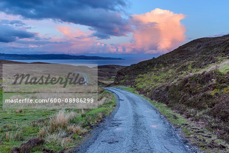 Old winding single track road in spring with cumulonimbus clouds at sunset on the Isle of Skye in Scotland, United Kingdom