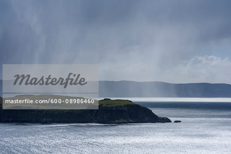 Sunlit sea cliffs and rainclouds along the coast of the Isle of Skye in Scotland, United Kingdom Sunlit sea cliffs and rainclouds along the coast of the Isle of Skye in Scotland, United Kingdom
