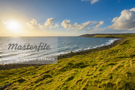 Rocky coastal beach with sun shining over the ocean on the Isle of Skye in Scotland, United Kingdom