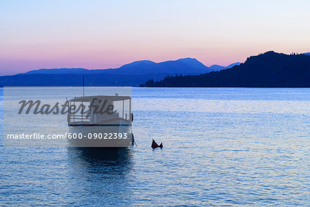 Silhouette of boat on Lake Garda (Lago di Garda) at dusk in Garda in Veneto, Italy