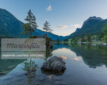 Lake Hintersee with mountains and trees growing on small, rock island at dawn at Ramsau in the Berchtesgaden National Park in Upper Bavaria, Bavaria, Germany