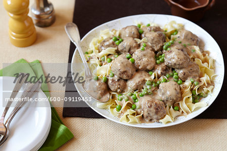 Meatballs in cream sauce on noodles with peas