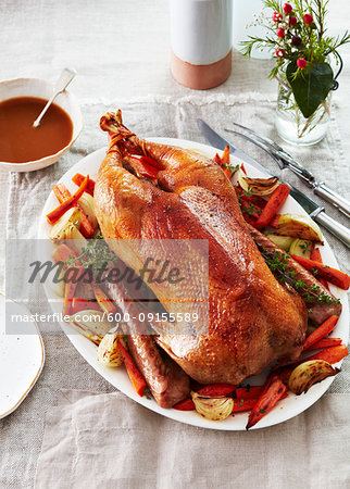 Roast goose on a platter with vegetables for a festive dinner