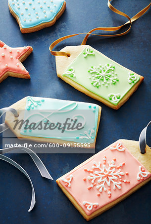 Close-up of festive sugar cookie gift tags decorated in pastel colors on a blue background