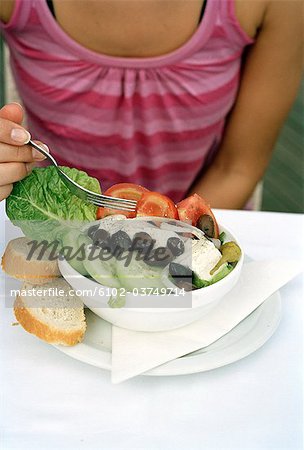 A woman eating Greek salad.