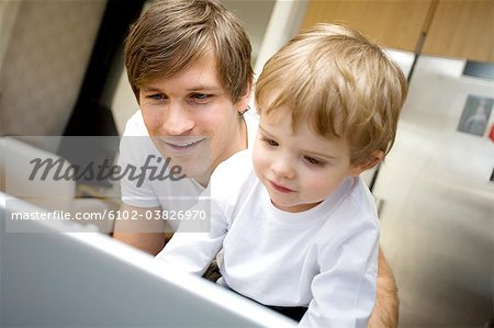 A father and a small child infront of a computer, at home, Sweden.