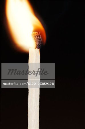 Close-up of flaming match stick against black background