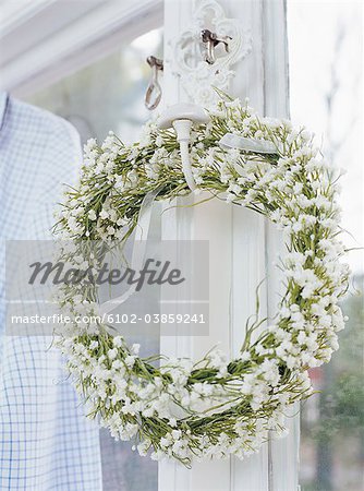 Wreath of white flowers hanging on window, close-up