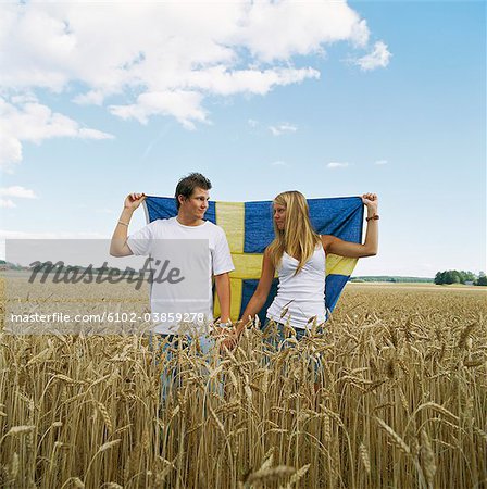 Couple holding Swedish flag in field