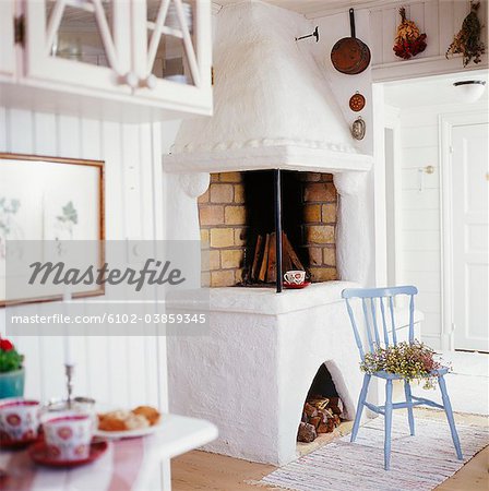 Fireplace in living room with chair and flowers in front