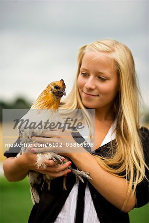 A teenage girl holding a hen, Sweden.