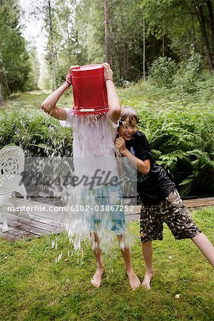 Boys playing with water in a garden a summer day, Sweden.