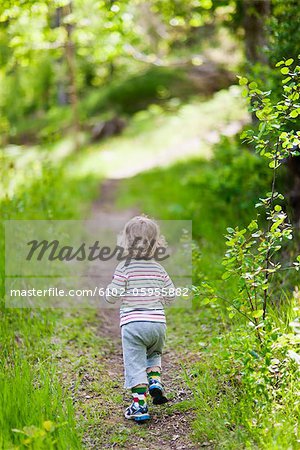 Boy running along path in forest