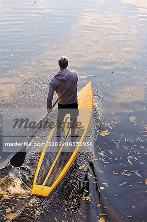 Man rowing paddle board in water, elevated view Man rowing paddle board in water, elevated view