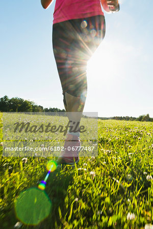 Low section of woman jogging in meadow