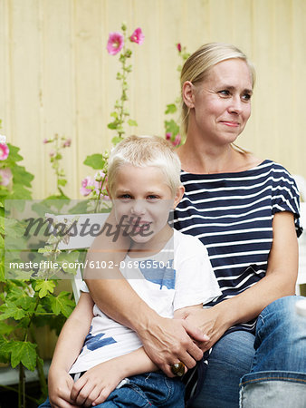 Mother and boy sitting in front of summer cottage