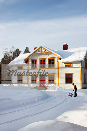 Woman removing snow from driveway