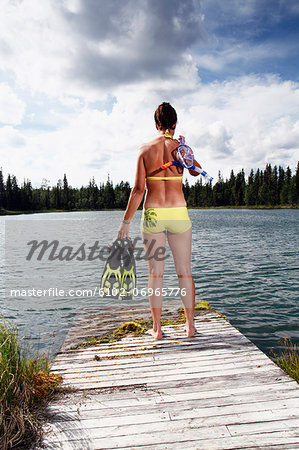 Woman holding diving flippers on jetty