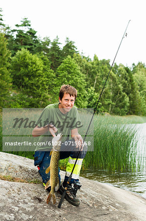 Smiling teenage boy with caught fish