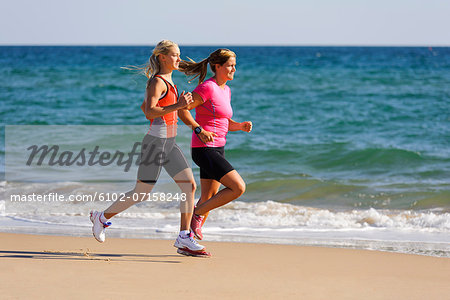 Young women running on beach, Algarve, Portugal