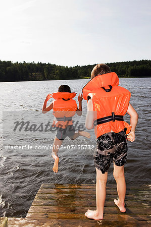 Boys jumping into water from jetty