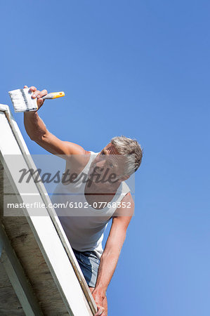 Mature man painting gable, Sweden